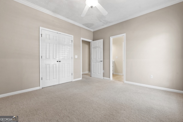 unfurnished bedroom featuring a textured ceiling, a closet, ceiling fan, ornamental molding, and light colored carpet