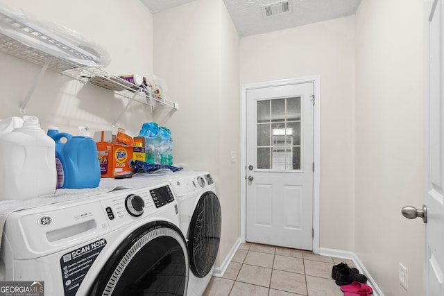 washroom featuring independent washer and dryer, a textured ceiling, and light tile patterned flooring