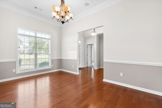 spare room with crown molding, a chandelier, and dark wood-type flooring