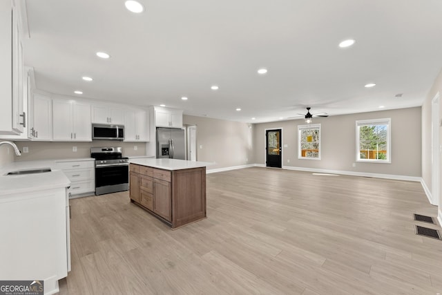 kitchen featuring stainless steel appliances, ceiling fan, sink, white cabinets, and a kitchen island