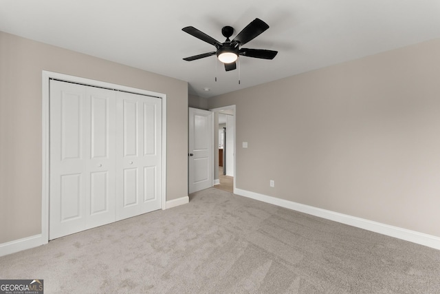 unfurnished bedroom featuring ceiling fan, a closet, and light carpet