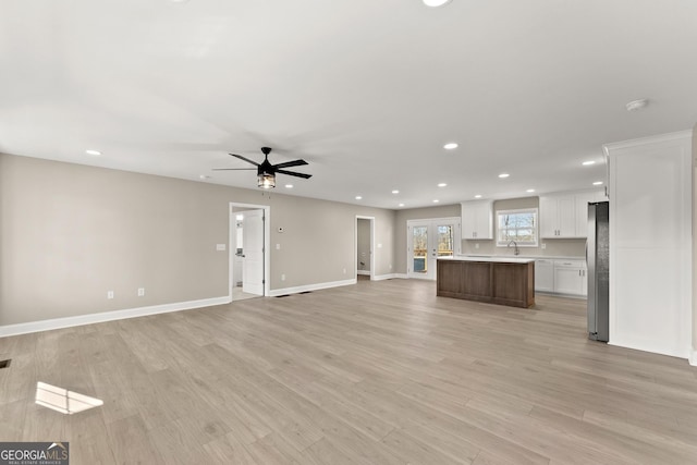 unfurnished living room with ceiling fan, light hardwood / wood-style flooring, french doors, and sink