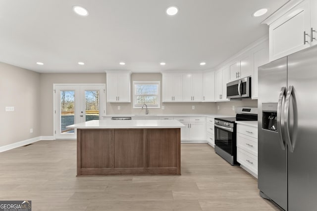 kitchen with appliances with stainless steel finishes, french doors, sink, white cabinets, and a center island