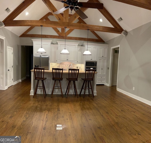 kitchen with dark hardwood / wood-style flooring, appliances with stainless steel finishes, a breakfast bar, a spacious island, and decorative light fixtures