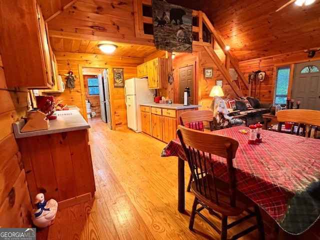 dining room featuring light hardwood / wood-style flooring, wooden walls, and wooden ceiling