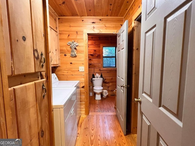 bathroom featuring wood walls, wooden ceiling, hardwood / wood-style floors, washing machine and dryer, and toilet