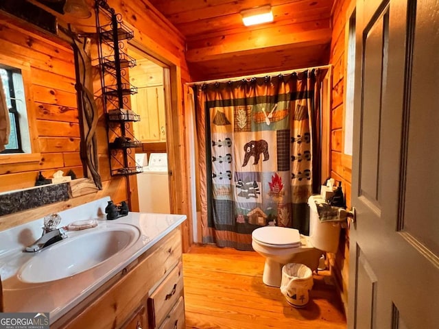 bathroom featuring hardwood / wood-style floors, wooden ceiling, wooden walls, and washer / clothes dryer