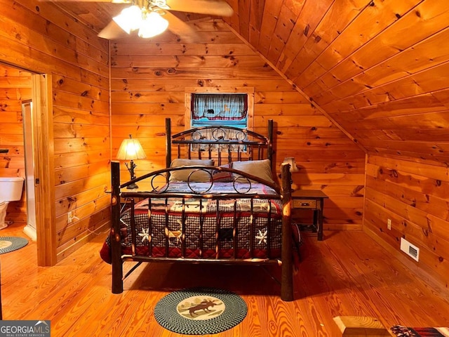 bedroom featuring light hardwood / wood-style floors, wood ceiling, wooden walls, and vaulted ceiling