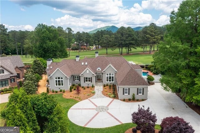 view of front of home featuring a mountain view, a front yard, and a swimming pool