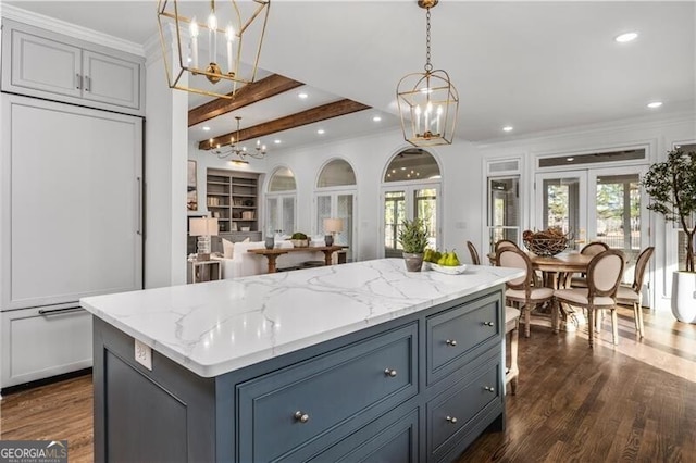 kitchen featuring hanging light fixtures, a kitchen island, light stone countertops, dark hardwood / wood-style floors, and french doors