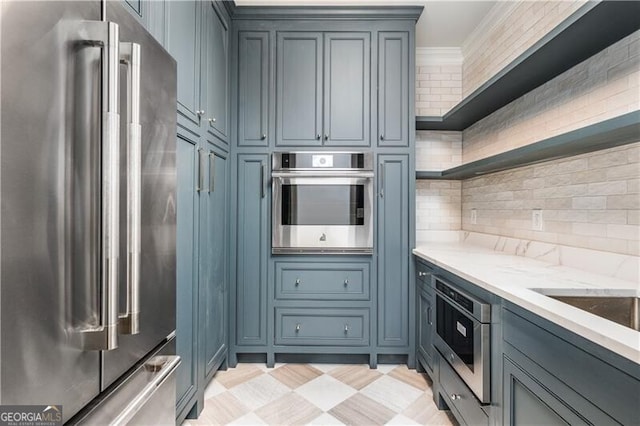 kitchen featuring appliances with stainless steel finishes, light stone counters, and backsplash