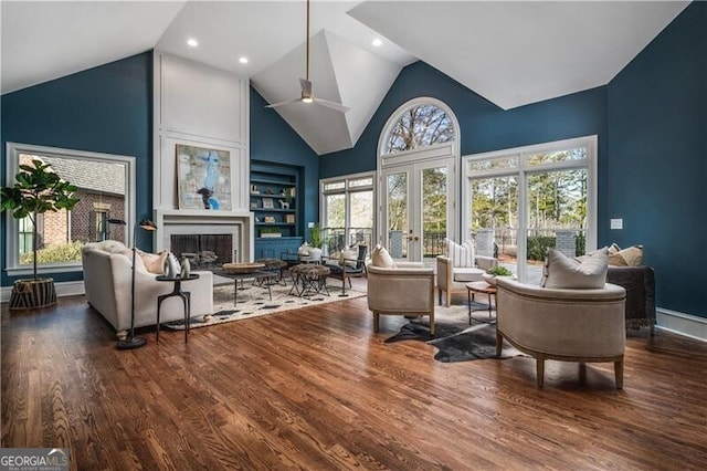 living room with a large fireplace, high vaulted ceiling, hardwood / wood-style flooring, and a healthy amount of sunlight