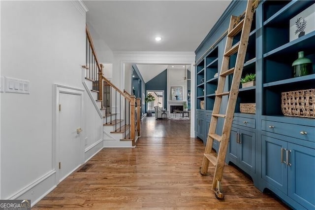 foyer entrance with ceiling fan, hardwood / wood-style flooring, ornamental molding, and vaulted ceiling