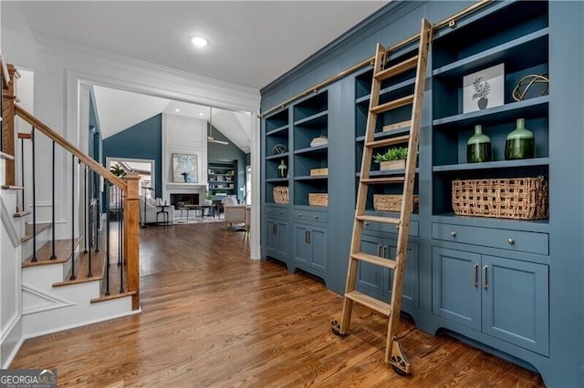 interior space featuring dark wood-type flooring, ornamental molding, lofted ceiling, and built in shelves