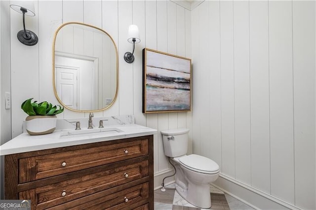 bathroom featuring vanity, toilet, and wooden walls