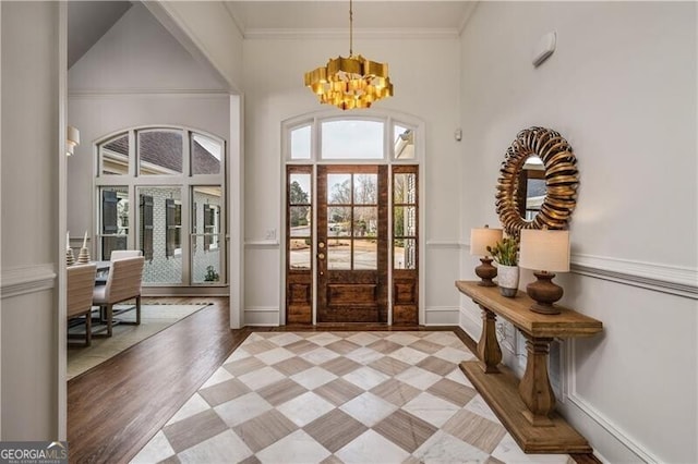 foyer featuring ornamental molding, wood-type flooring, and an inviting chandelier