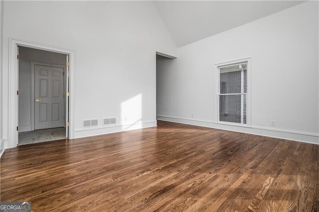 spare room with dark wood-type flooring and high vaulted ceiling