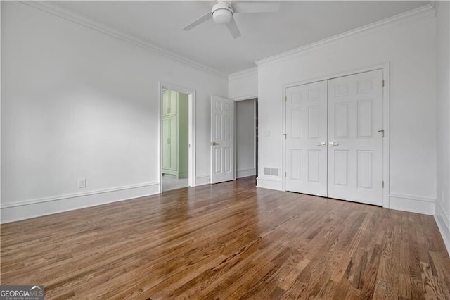 unfurnished bedroom with hardwood / wood-style floors, crown molding, a closet, and ceiling fan