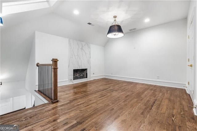 unfurnished living room featuring lofted ceiling with skylight, hardwood / wood-style floors, and a fireplace