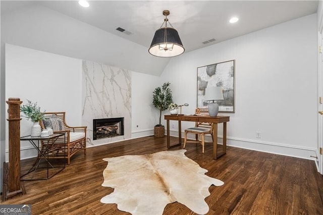 office space with vaulted ceiling, dark hardwood / wood-style flooring, and a fireplace