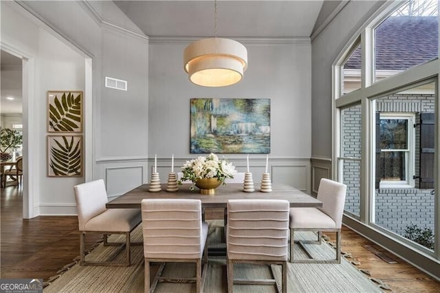 dining area with ornamental molding, vaulted ceiling, and hardwood / wood-style flooring