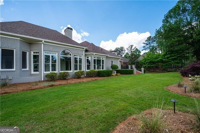 rear view of property featuring a lawn