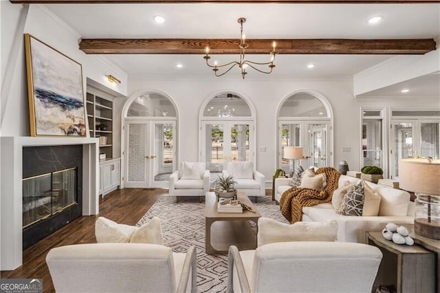 living room with french doors, beamed ceiling, a high end fireplace, an inviting chandelier, and dark hardwood / wood-style flooring