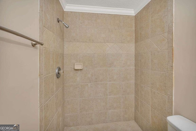 bathroom with toilet, crown molding, and a tile shower