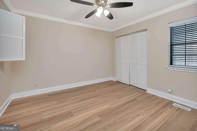 unfurnished bedroom featuring light hardwood / wood-style floors, a closet, crown molding, and ceiling fan