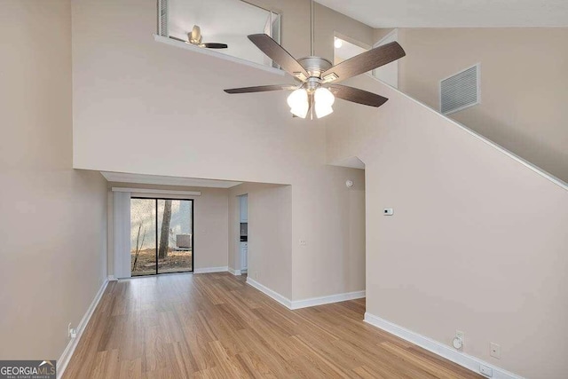 unfurnished living room with ceiling fan, high vaulted ceiling, and light wood-type flooring