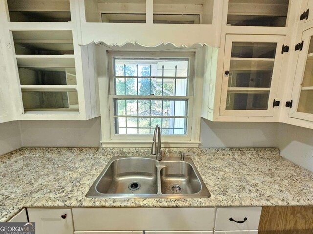 kitchen with white cabinets, light stone countertops, and sink