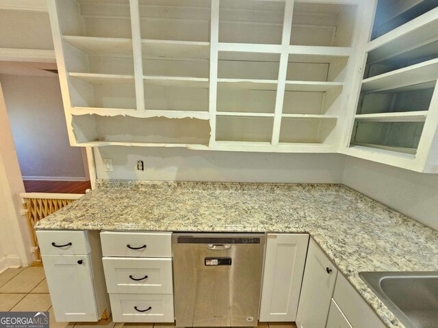 kitchen with dishwasher, sink, light tile patterned floors, white cabinets, and light stone counters