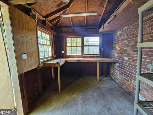 misc room featuring concrete flooring and brick wall