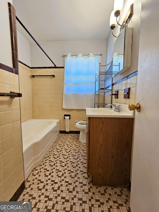 full bathroom featuring vanity, toilet, tile walls, and washtub / shower combination