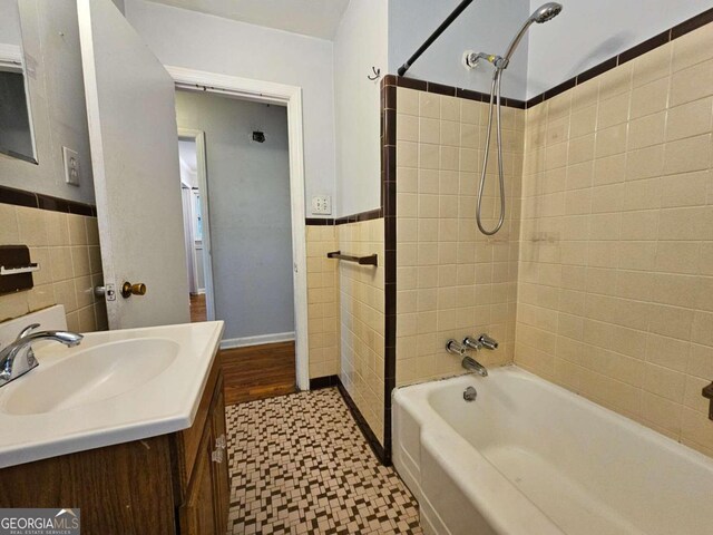 bathroom with vanity, tiled shower / bath, and tile walls