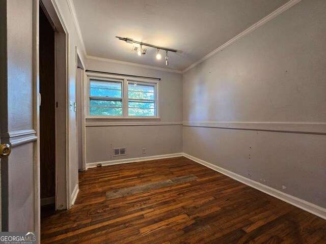 spare room with ornamental molding, track lighting, and dark hardwood / wood-style flooring