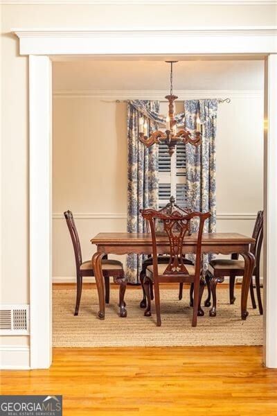 dining space with wood-type flooring and an inviting chandelier