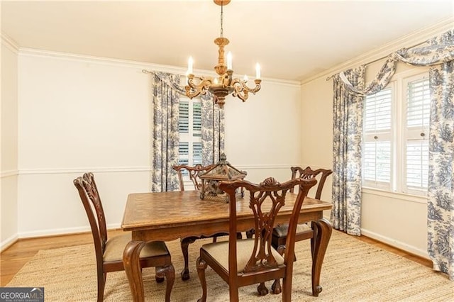 dining room featuring light wood-type flooring, ornamental molding, a wealth of natural light, and an inviting chandelier