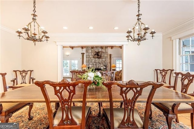 tiled dining room with a chandelier, a fireplace, a healthy amount of sunlight, and ornamental molding