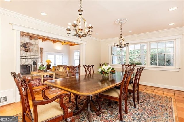 tiled dining area featuring a fireplace, a chandelier, a wealth of natural light, and ornamental molding