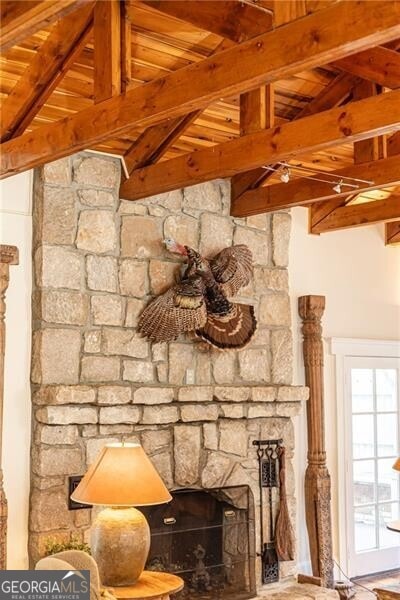 room details featuring beam ceiling, a stone fireplace, and wooden ceiling