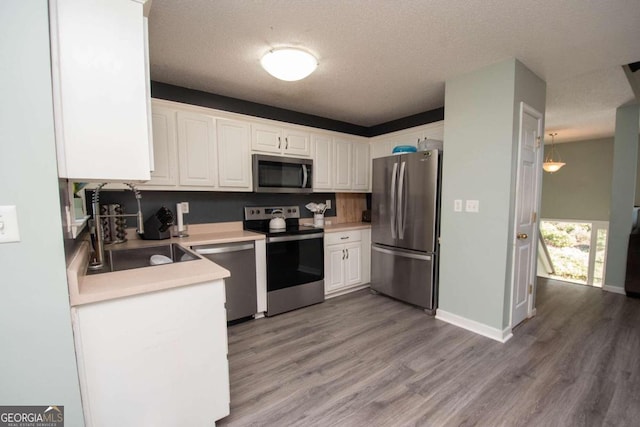 50 Carthedge Trce, Newnan, GA 30263 - kitchen featuring light wood finished floors, a sink, white cabinetry, a textured ceiling, and appliances with stainless steel finishes