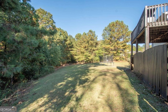 view of yard featuring a wooden deck and a trampoline