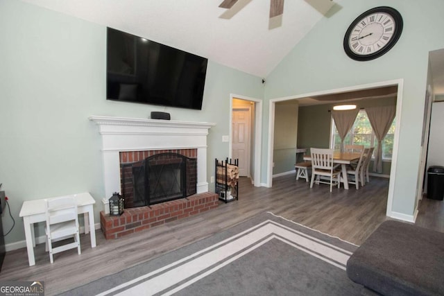 living room with ceiling fan, high vaulted ceiling, wood-type flooring, and a fireplace