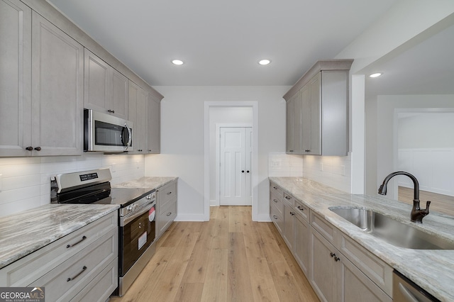 kitchen featuring sink, gray cabinetry, stainless steel appliances, and light wood-type flooring