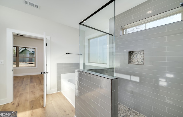 bathroom with wood-type flooring and independent shower and bath