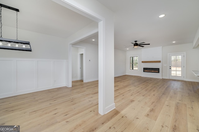 unfurnished living room featuring a fireplace, plenty of natural light, light hardwood / wood-style flooring, and ceiling fan