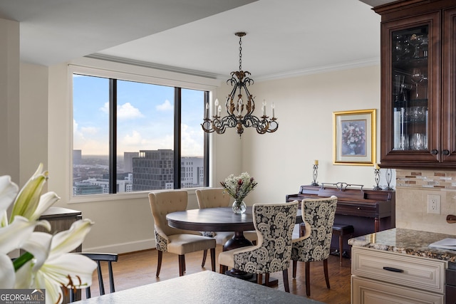 dining space with a chandelier, wood finished floors, baseboards, a view of city, and crown molding