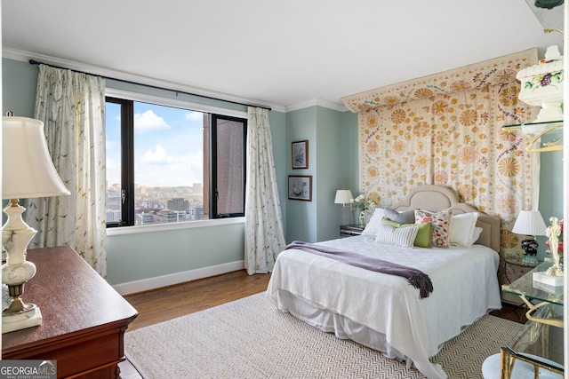 bedroom featuring baseboards, crown molding, and wood finished floors