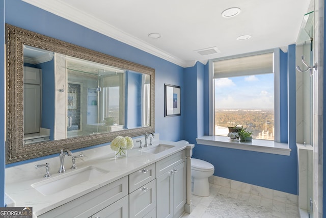 bathroom with double vanity, crown molding, toilet, and a sink